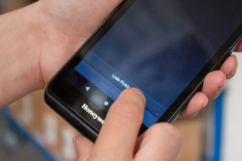 Mitarbeiter erhalten über das Handgerät Anweisungen für die Kommissionierung